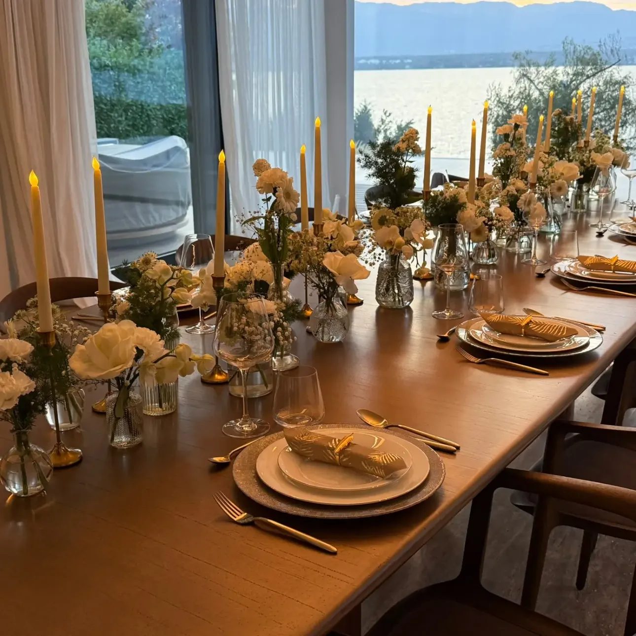 Scénographie de table pour une réception au bord du lac : fleurs crème et bougies